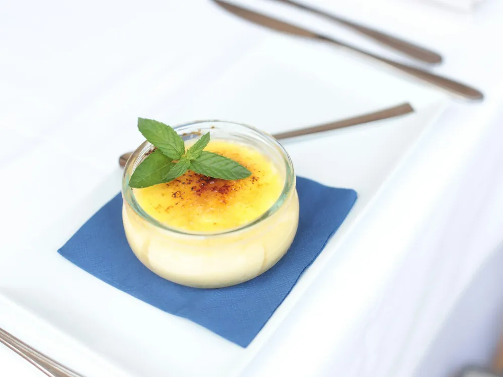 Crème brûlée à la vanille caramélisée, décorée d'une feuille de menthe