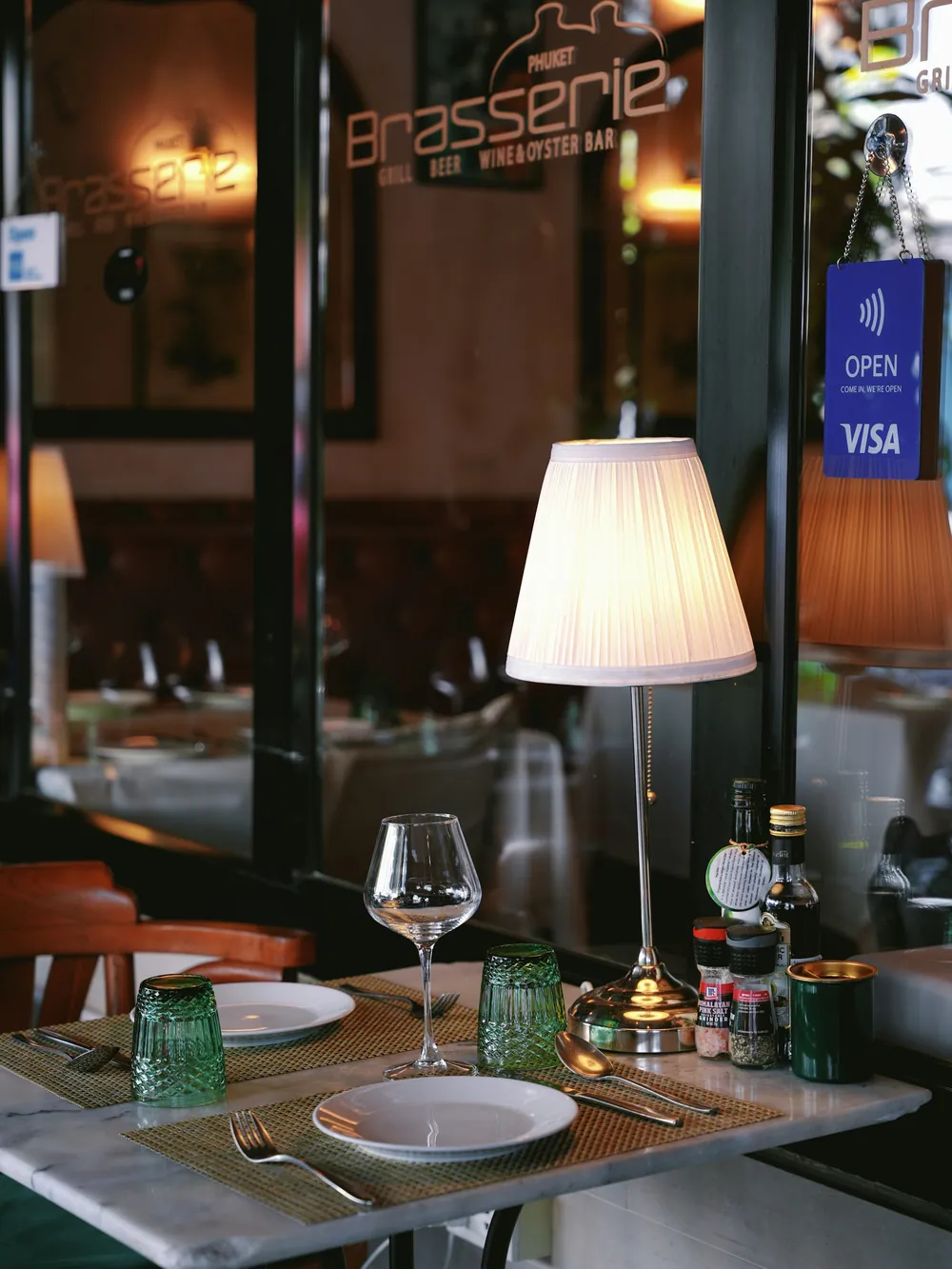 Devanture et tables dressées de la brasserie, enseigne « Brasserie » au-dessus de la salle