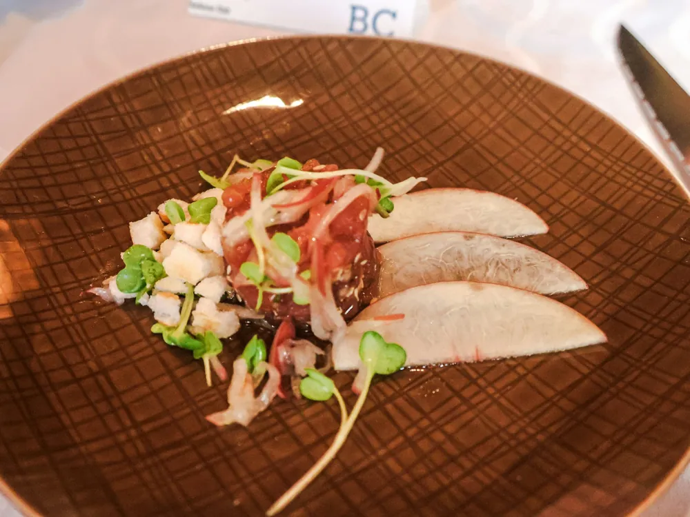 Poisson du jour dressé avec des jeunes pousses sur une assiette de grès