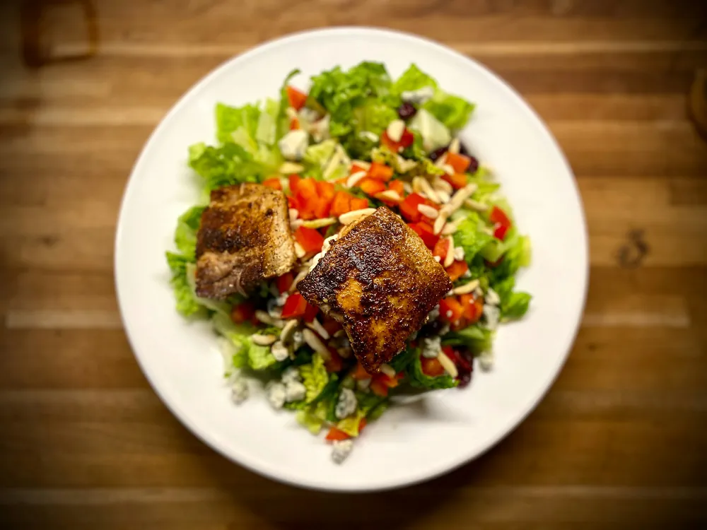 Grande salade de saison colorée servie dans une assiette blanche, vue de dessus