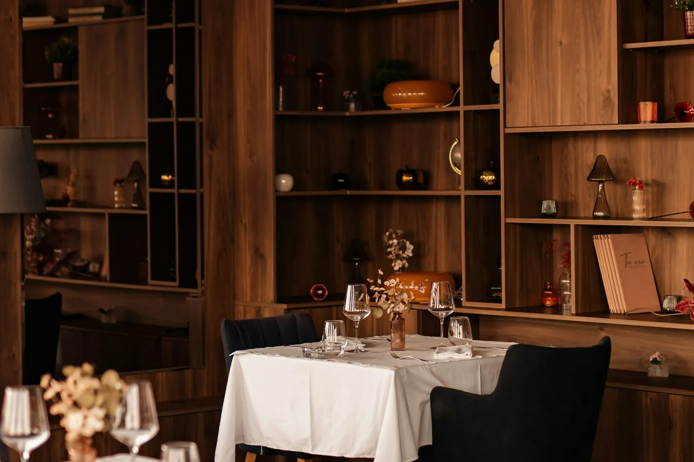Tables dressées en salle avec nappes blanches et étagères de bouteilles