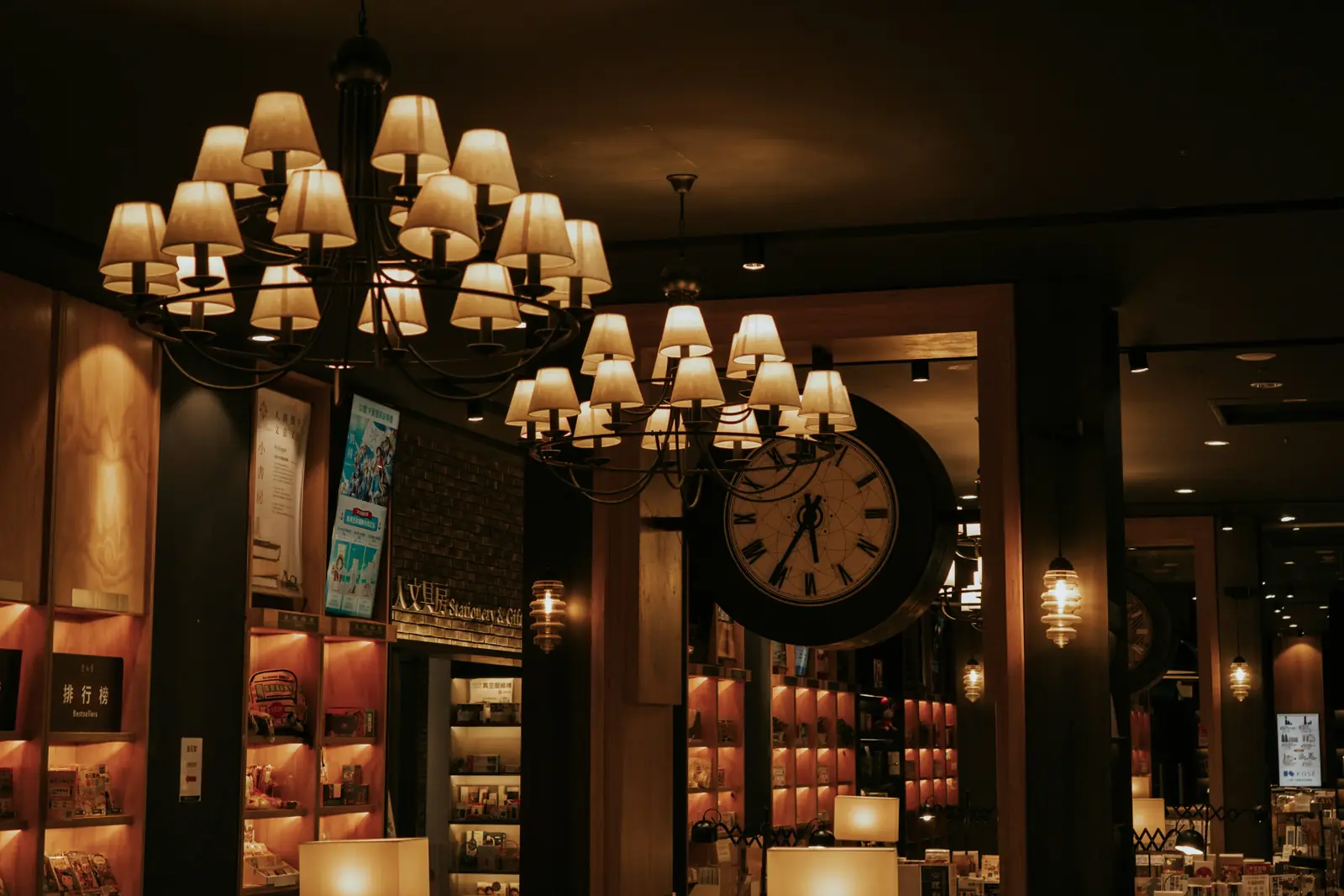 Salle de la brasserie éclairée par des lustres, comptoir et horloge murale